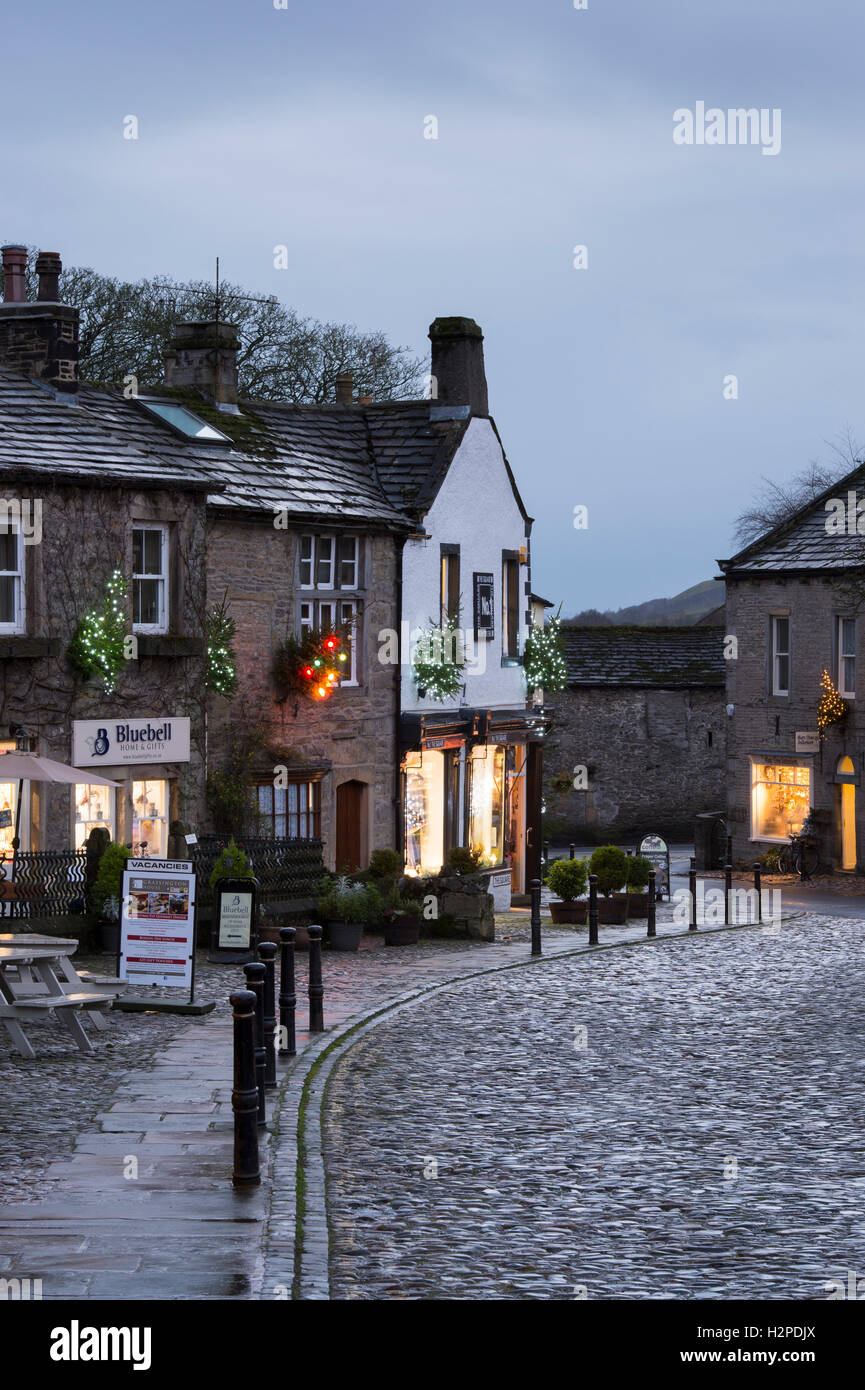 Lumières de Noël coloré égayer une sombre soirée d'hiver - Malham Village, Yorkshire Dales National Park, England. Banque D'Images