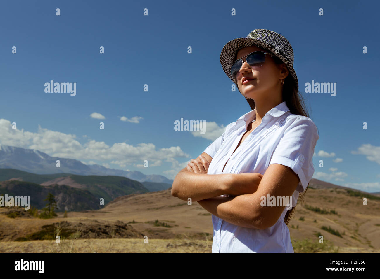 Femme avec des lunettes et un chapeau regarde ailleurs sur le fond des montagnes Banque D'Images
