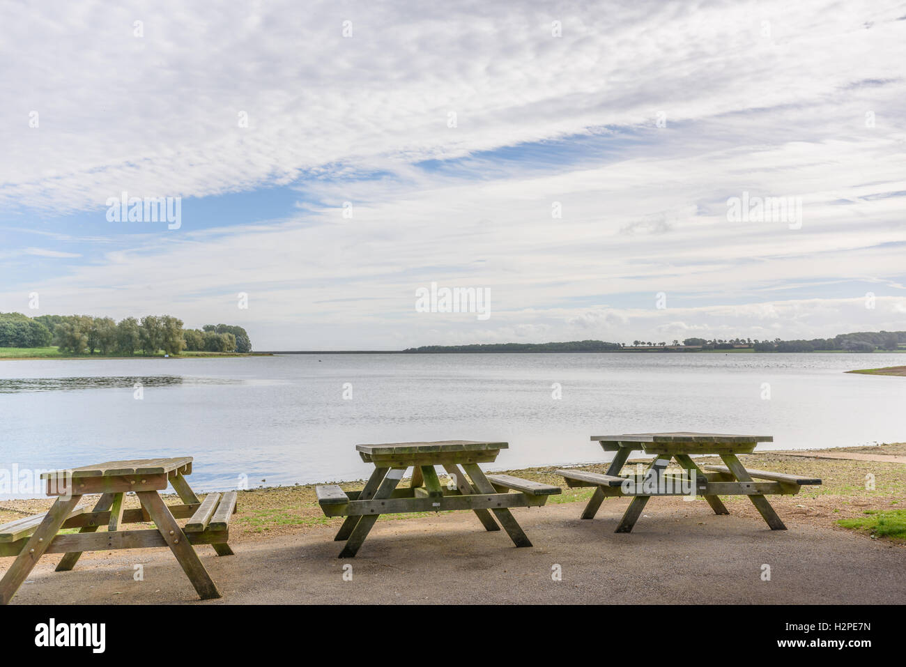 Trois tables de pique-nique sur la rive sur Rutland Water lake. Banque D'Images