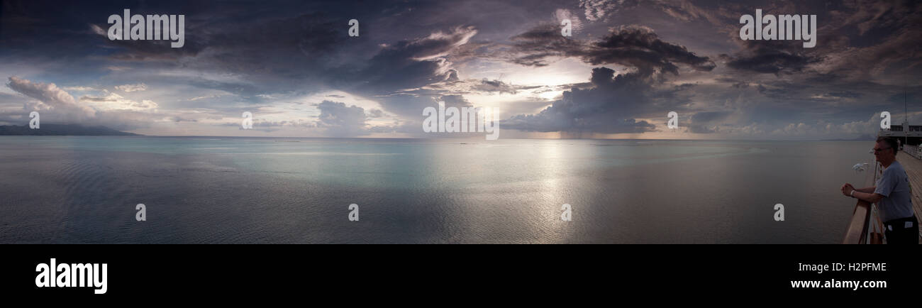 Un homme regarde le coucher du soleil sur l'océan Pacifique Sud depuis le pont d'un navire. Banque D'Images