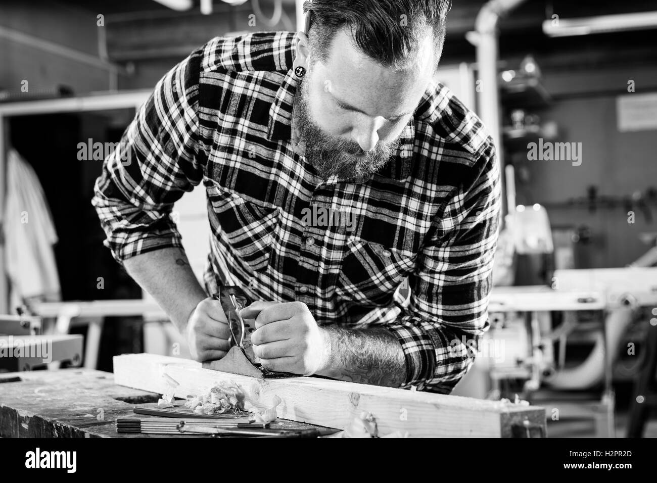 Carpenter travailler avec avion sur la planche en bois dans l'atelier Banque D'Images