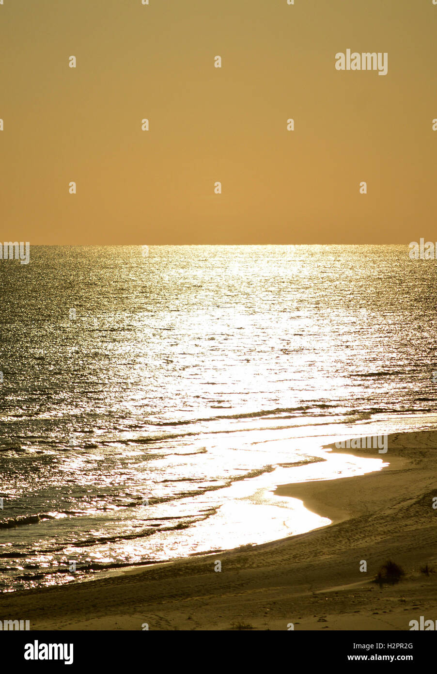 Une plage de sable blanc avec de l'eau scintillant sur l'au coucher du soleil. Banque D'Images