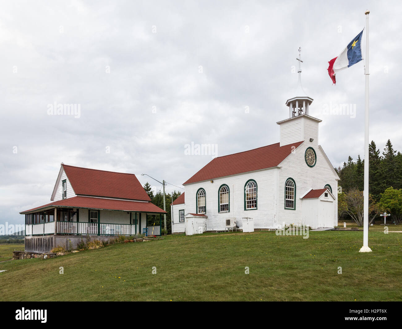 Le drapeau acadien va à l'avant de la chapelle de Sainte Anne de Beaumont et le presbytère qui ont été construit en1842. Banque D'Images
