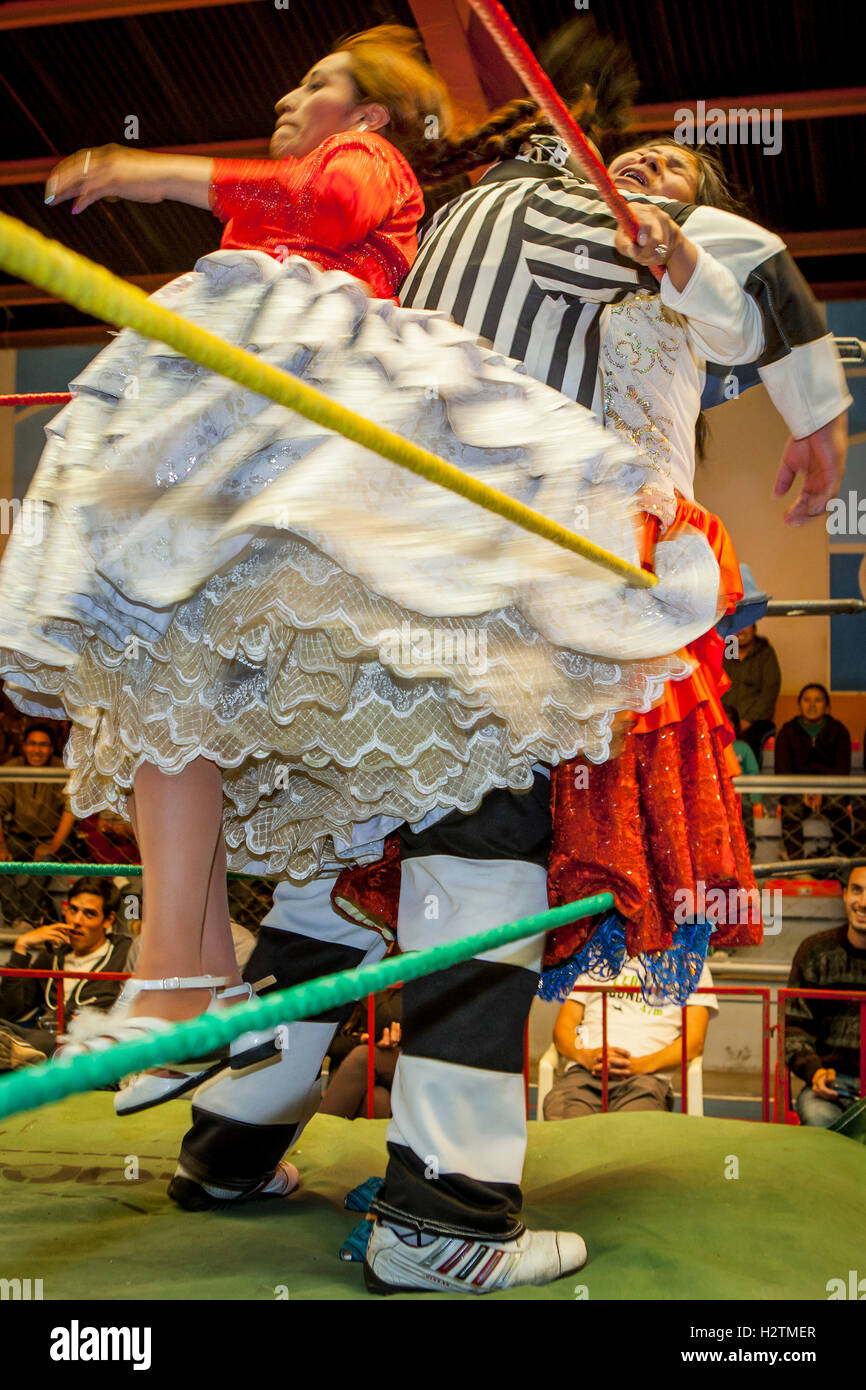 Lucha Libre. Combat entre Dina avec jupe orange et Benita la Intocable , cholitas lutteurs femelles ,avec arbitre au milieu Banque D'Images