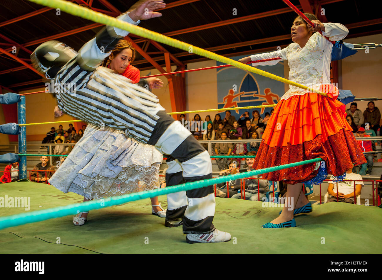 Lucha Libre. Combat entre Dina avec jupe orange et Benita la Intocable , cholitas lutteurs femelles ,avec arbitre au milieu Banque D'Images