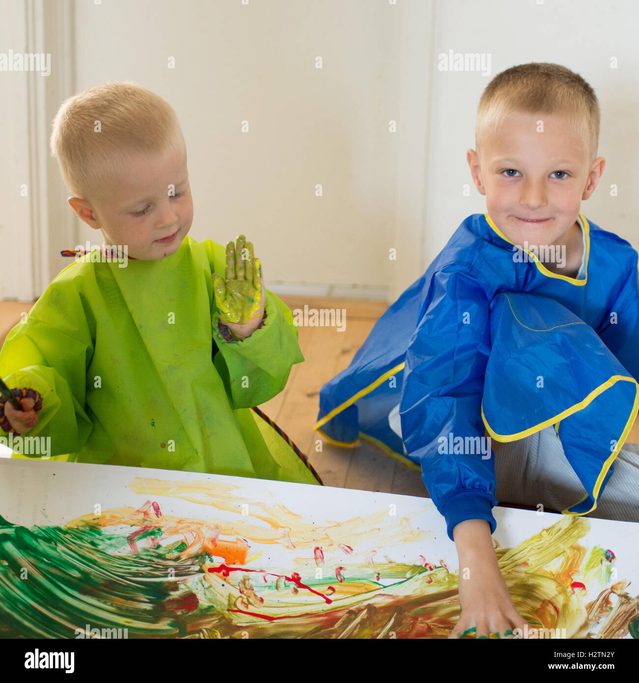 Les enfants peindre avec leurs mains sur du papier blanc sur le sol Banque D'Images