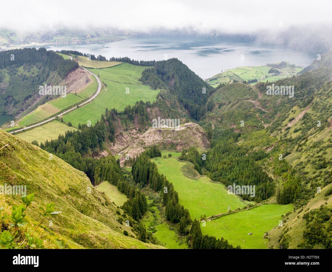 Route entre Lagoa Azul et Santiago et la vallée ci-dessous. La brume se déplace sur une route qui tourne au sommet du cratère, entre les lacs Banque D'Images