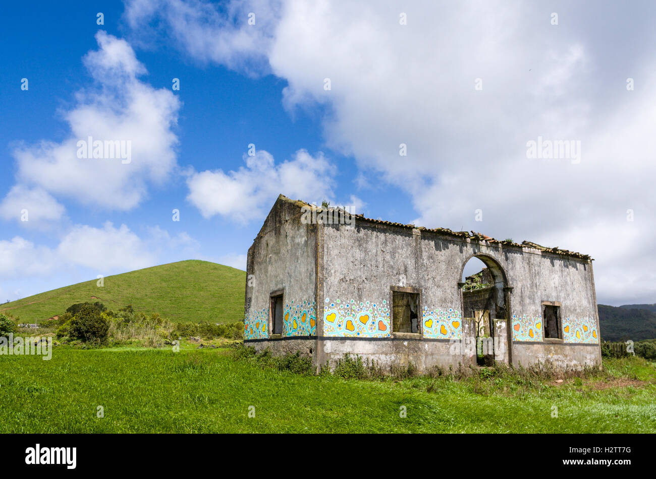 Cottage abandonné décoré par Yves Decoster. Un aperçu, sans toit cottage situé dans un pâturage verdoyant avec une colline derrière Banque D'Images