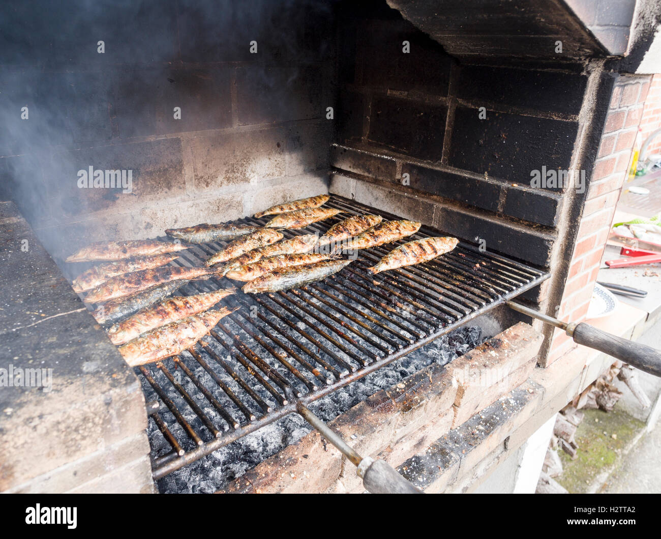 Les sardines grillées sur un barbecue des. Une grille pleine de sardines de cuisson ou de maquereau cuit sur un barbecue en brique sur un charbon de bois chaud Banque D'Images