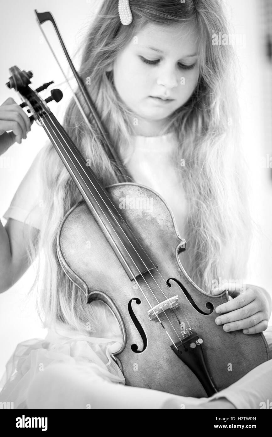 Image en noir et blanc d'une belle jeune fille aux cheveux longs jouant avec violon Banque D'Images