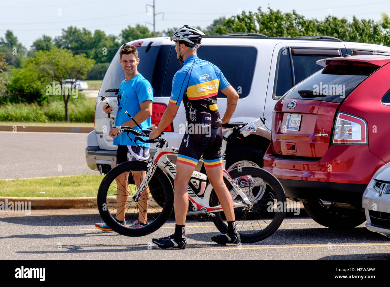 Un jeune homme en vélo gear s'apprête à faire du vélo tout en parlant à un autre homme. Oklahoma City, Oklahoma, USA. Banque D'Images