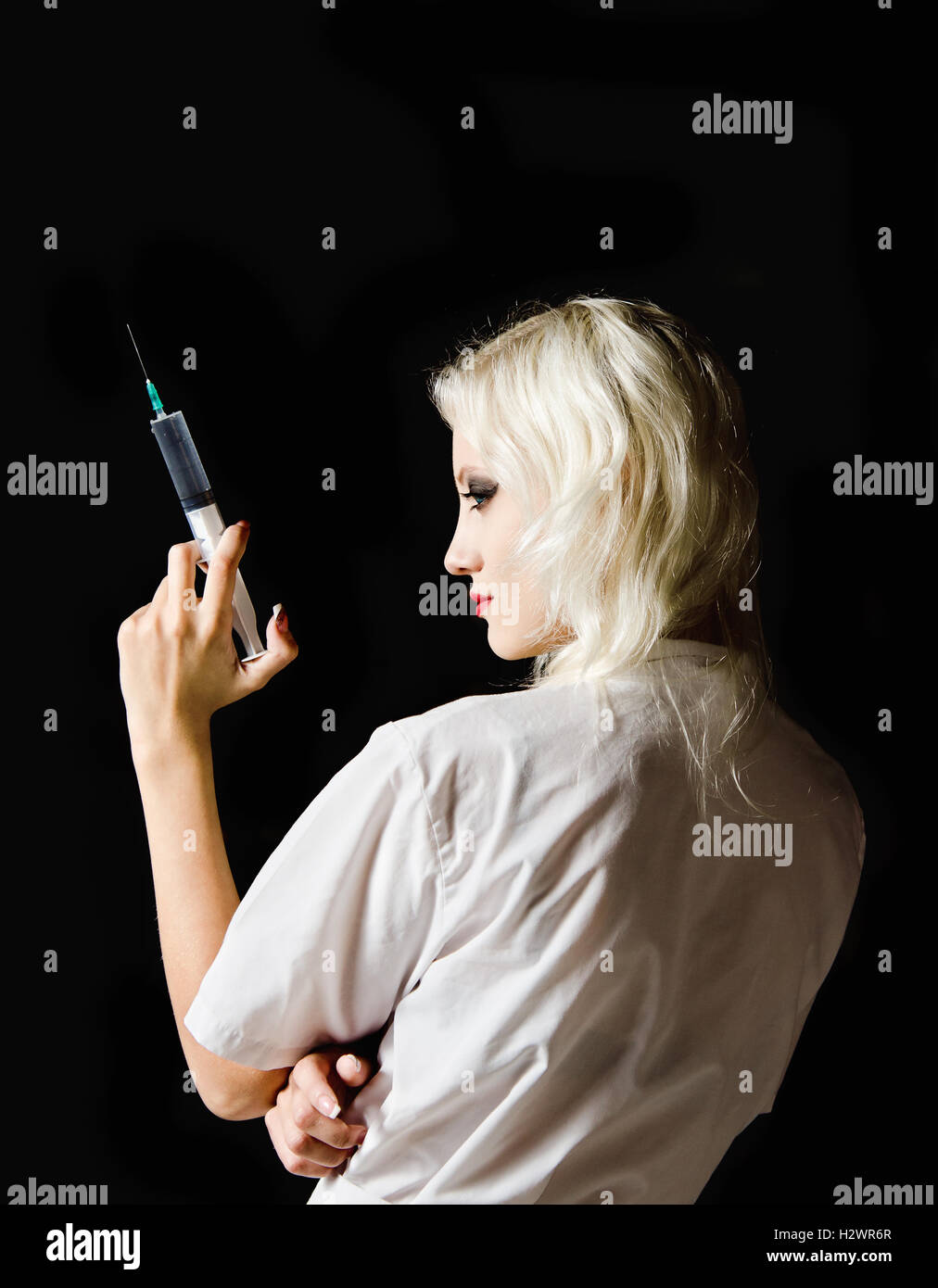 Belle jeune fille à l'image de l'infirmière avec la seringue à la main, vue arrière Banque D'Images