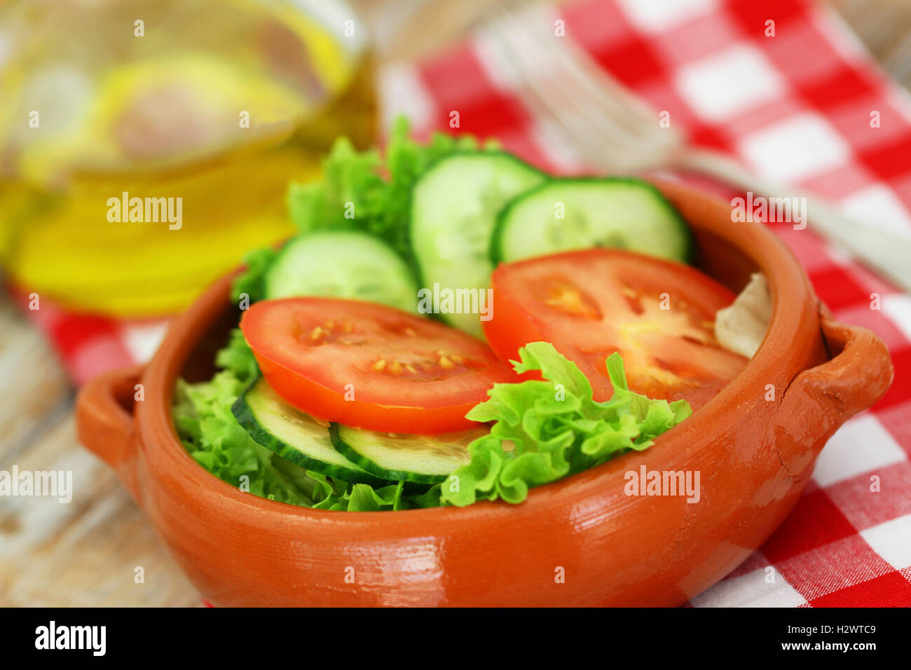 Salade verte fraîche composée de laitue, tomates et concombres en cuvette d'argile sur tissu à carreaux Banque D'Images Salade verte fraîche composée de laitue, tomates et concombres en cuvette d'argile sur tissu à carreaux Banque D'Images