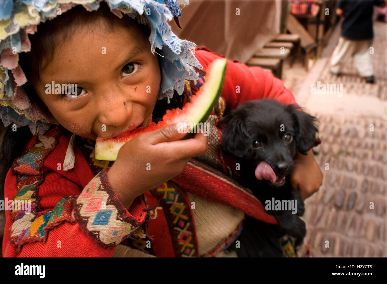 Une jeune fille vêtue d'un costume traditionnel de manger un morceau de pastèque de Pisac Dimanche Jour de marché. Pisac. Vallée Sacrée. Pisac, ou Banque D'Images