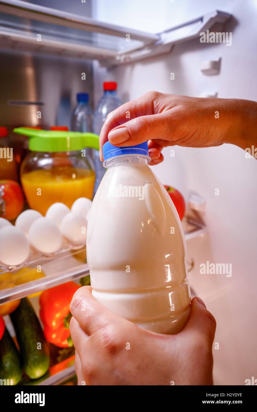 Femme prend le lait du réfrigérateur ouverte Banque D'Images