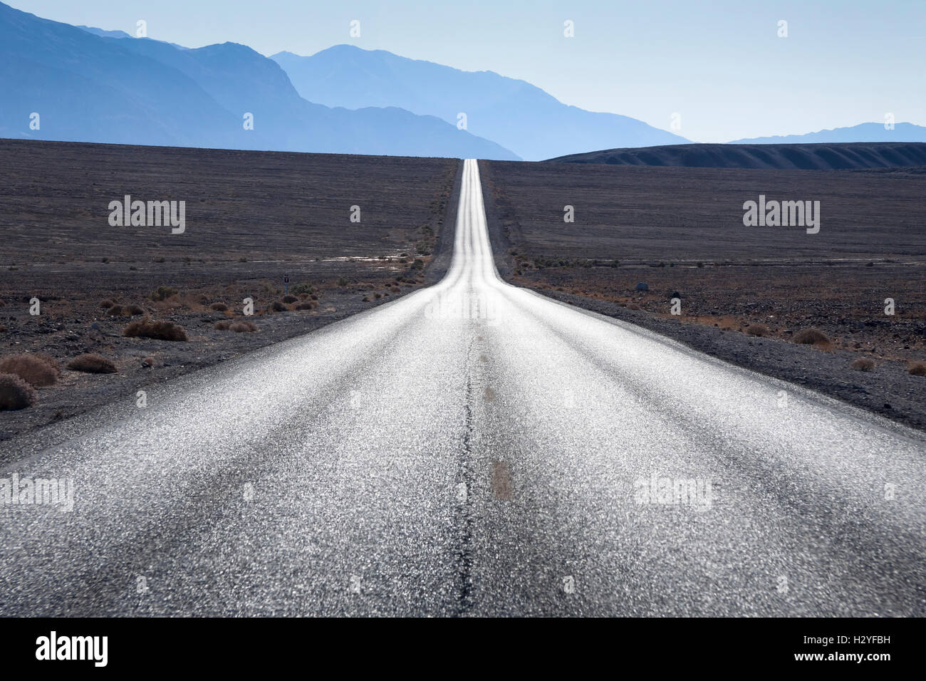 Route droite en direction de montagnes en horizon à Death Valley, Etats-Unis Banque D'Images