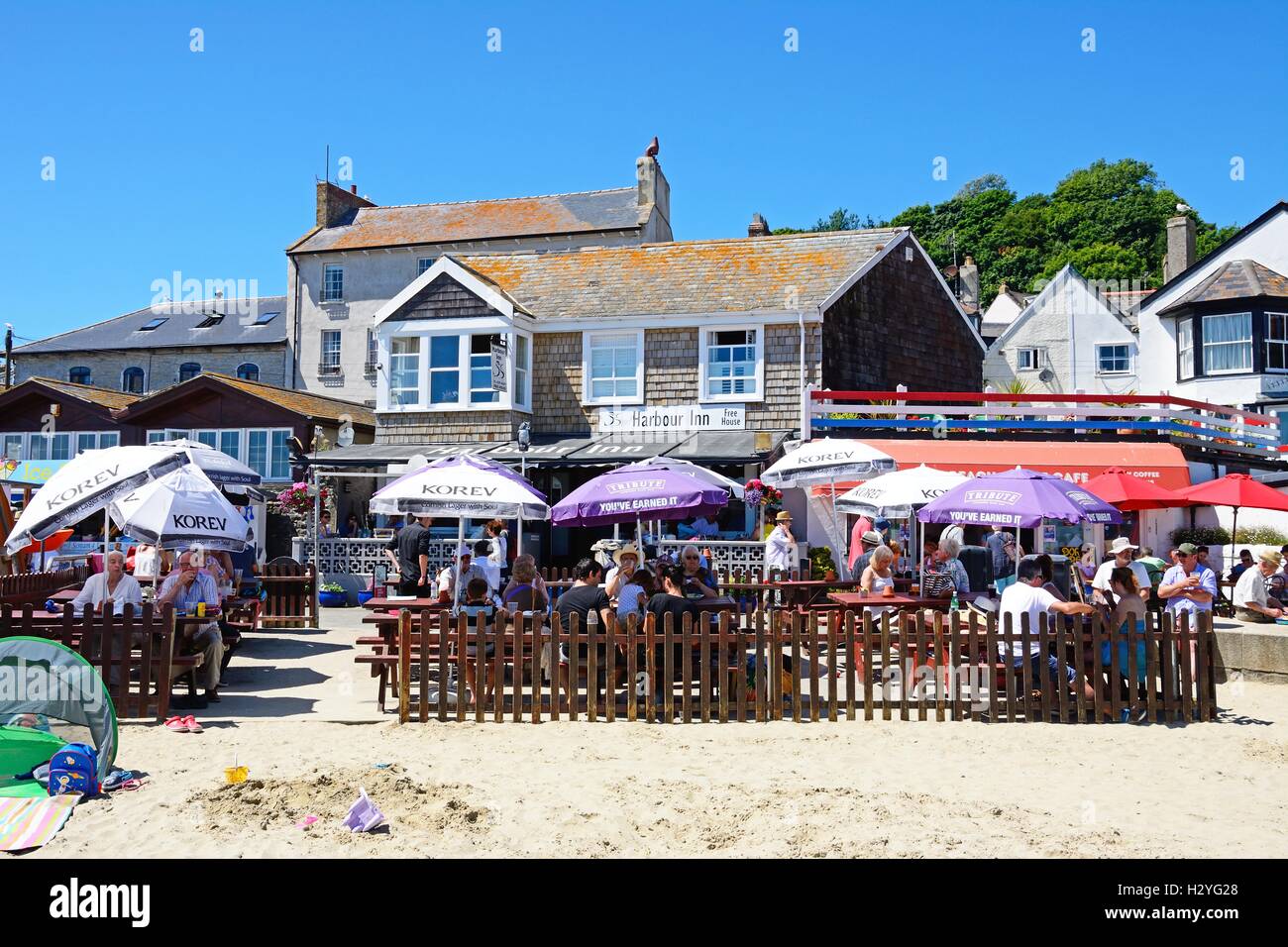 Les touristes sur une plage de détente avec café le port Inn pub à l'arrière, à Lyme Regis, dans le Dorset, Angleterre, Royaume-Uni, Europe de l'Ouest. Banque D'Images