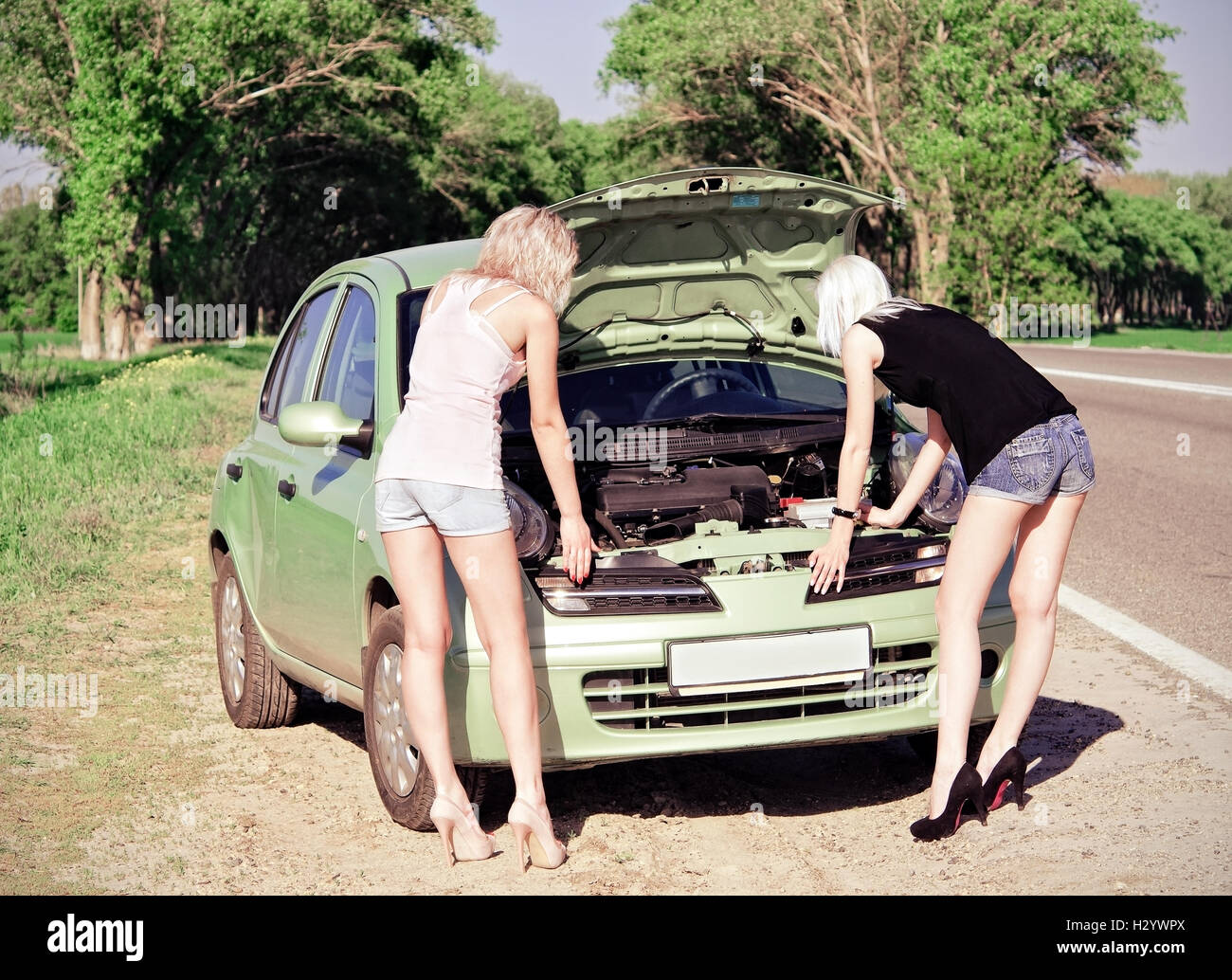 Deux blondes debout près de la voiture cassée Banque D'Images