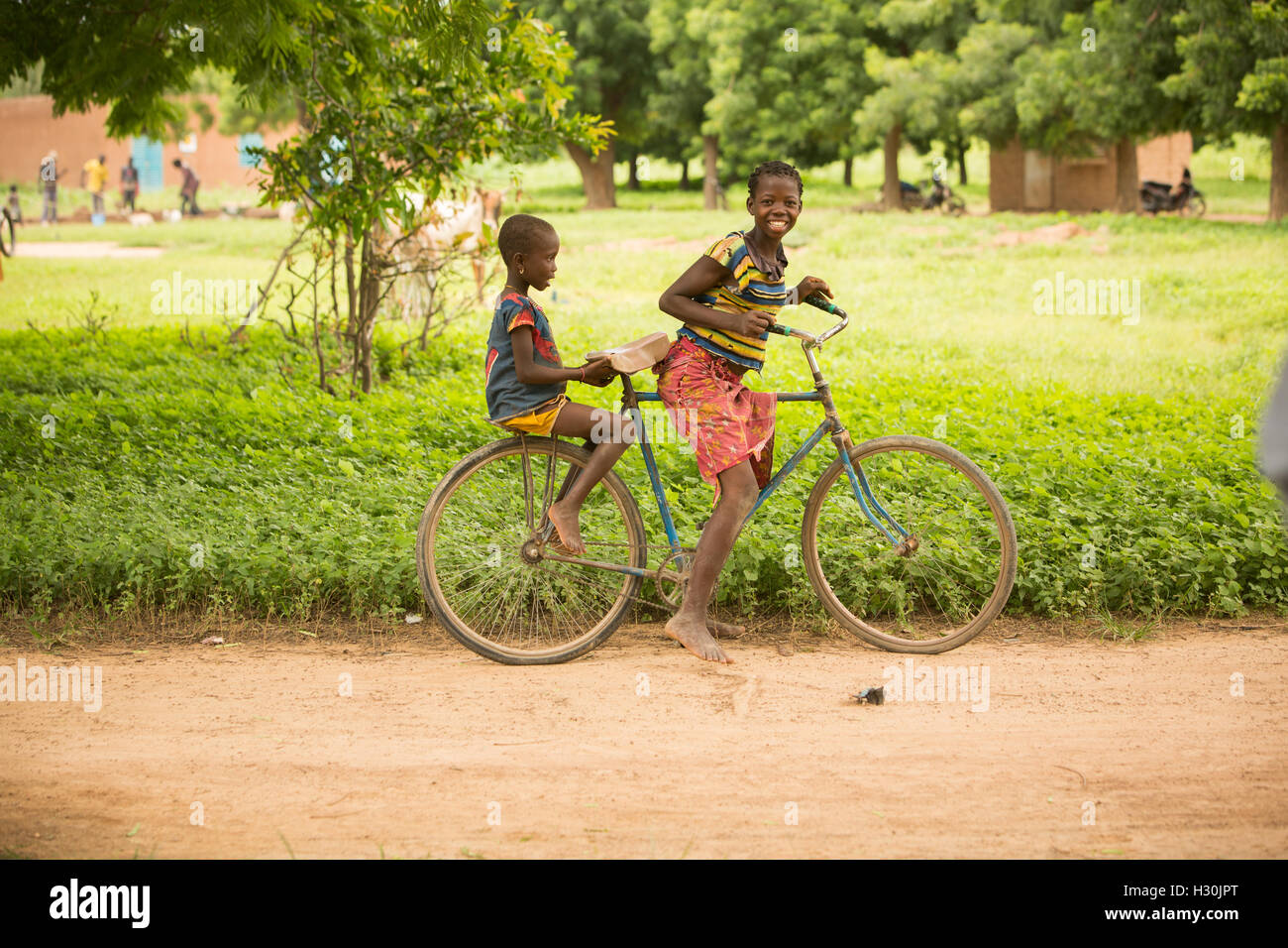 Des enfants heureux de rouler à bicyclette dans les régions rurales de Réo, Burkina Faso, du Département Afrique de l'Ouest. Banque D'Images