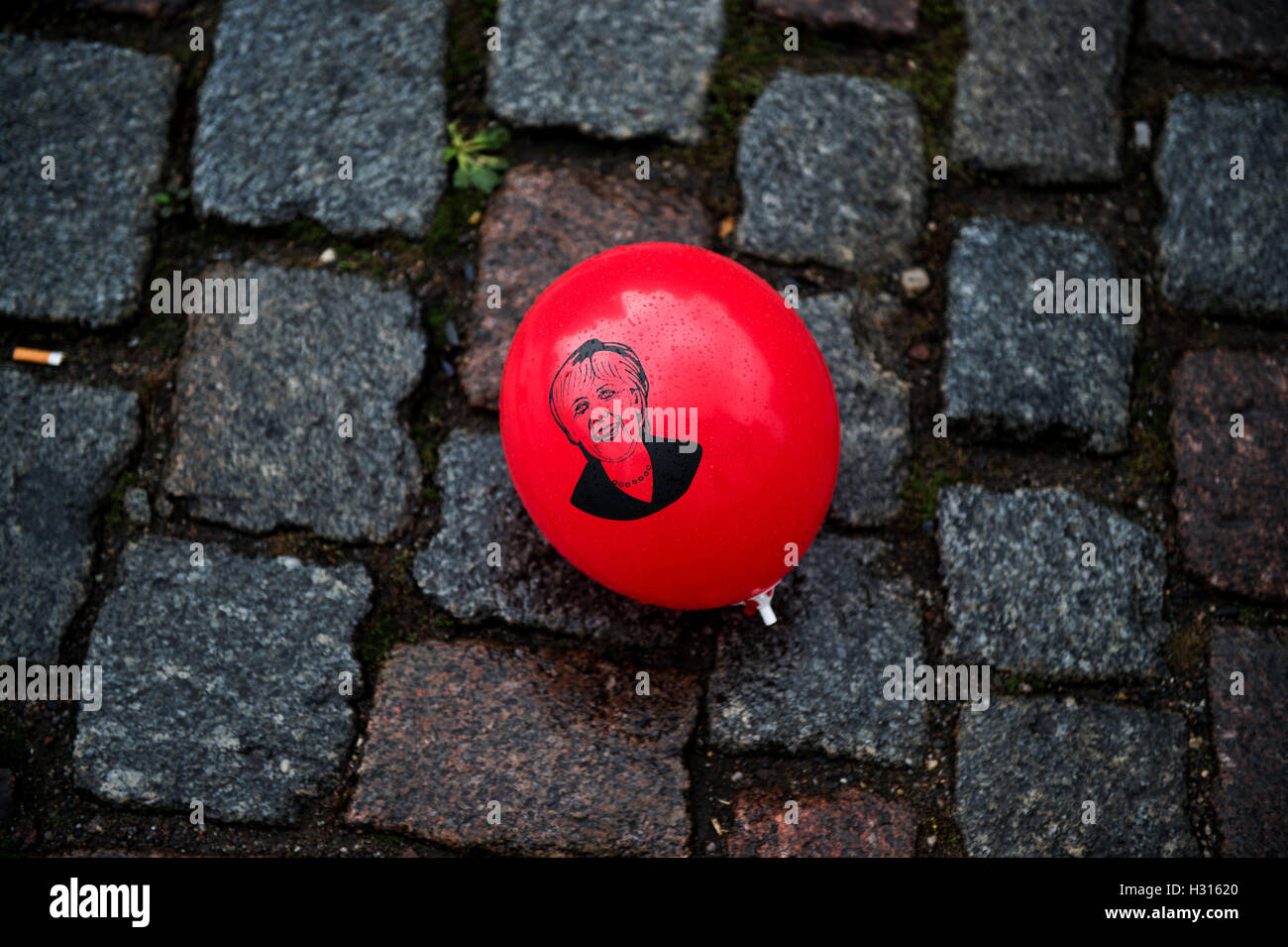 Dresde, Allemagne. 06Th Oct, 2016. Un ballon rouge avec un chiffre de la Chancelière allemande Anglea Merkel jette sur les pavés mouillés après une démonstration sur les rives de l'Elbe sous le pont Blaues Wunder' 'à Dresde, Allemagne, 03 octobre 2016. Les plus hauts représentants de l'Etat devraient à Dresde pour le mettre en surbrillance et de clôture des célébrations sur l'unité allemande 24. Photo : ARNO BURGI/dpa/Alamy Live News Banque D'Images