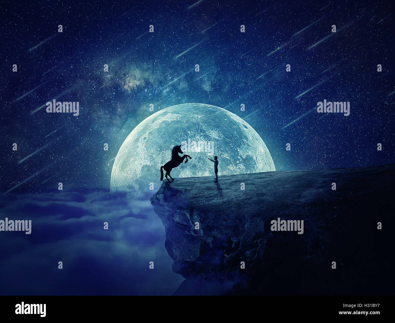 Scène de nuit avec un garçon debout au bord d'une falaise chasm tenter d'apprivoiser une licorne sauvage. Début d'une nouvelle amitié, fearle Banque D'Images