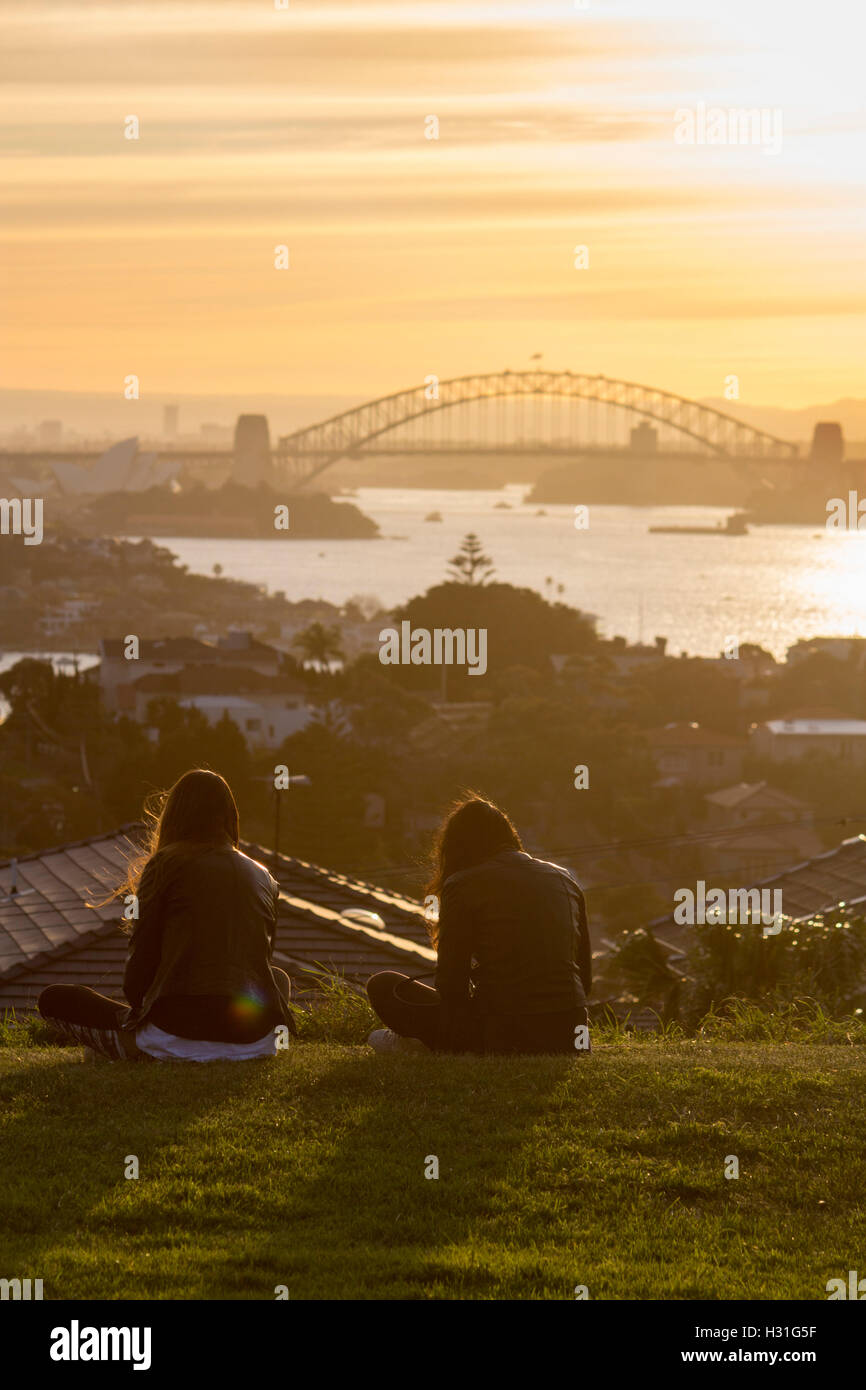Deux femmes regardant le coucher du soleil sur le port de Sydney avec le Harbour Bridge de Sydney NSW Australie distance Banque D'Images