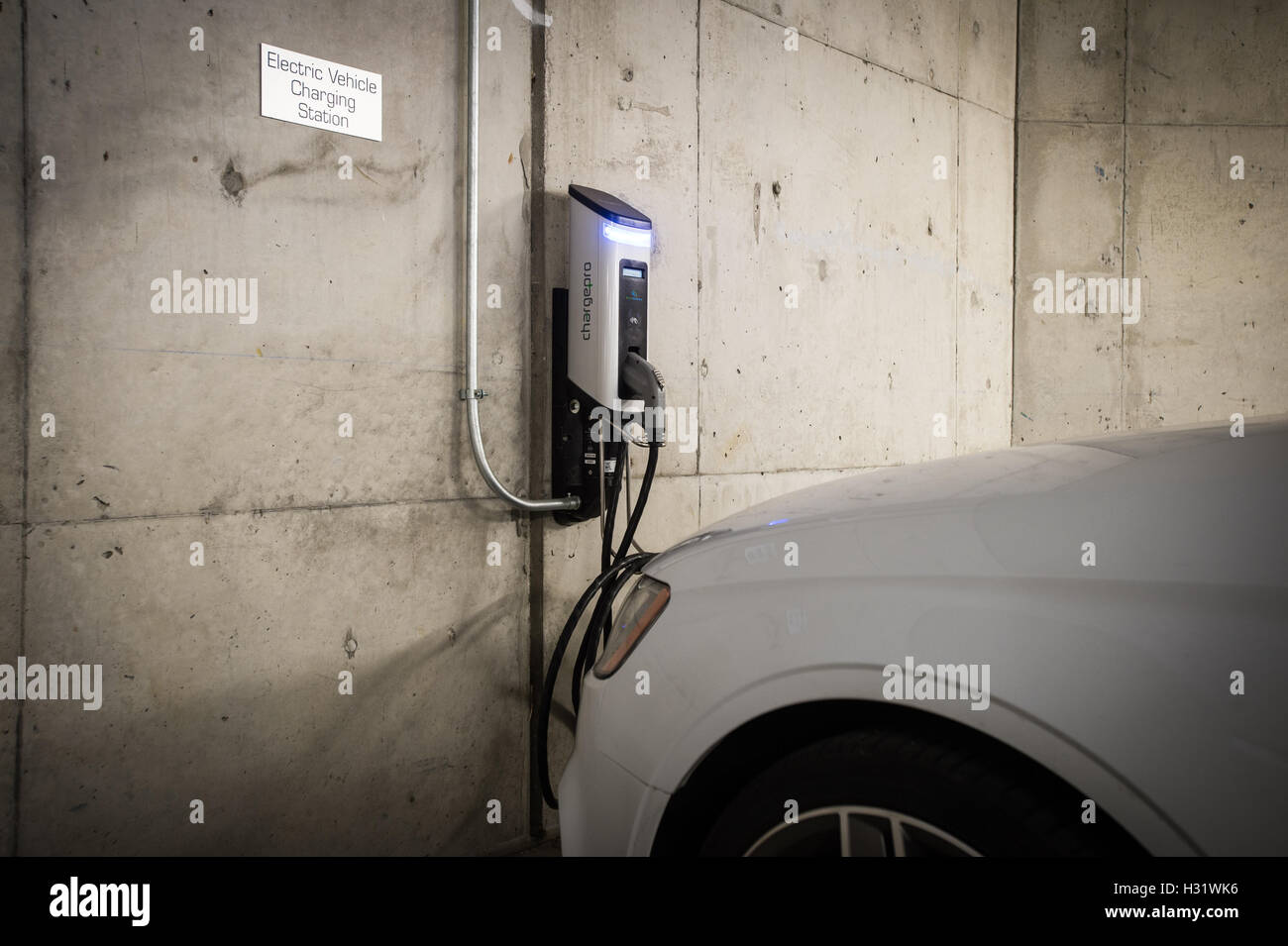 Une voiture électrique branché sur une station de recharge de véhicules électriques dans un garage. Banque D'Images