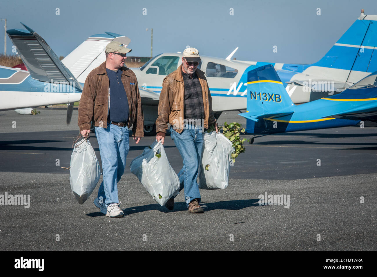 Deux hommes transporter des sacs dans un aéroport sur Tanger Island, en  Virginie Photo Stock - Alamy