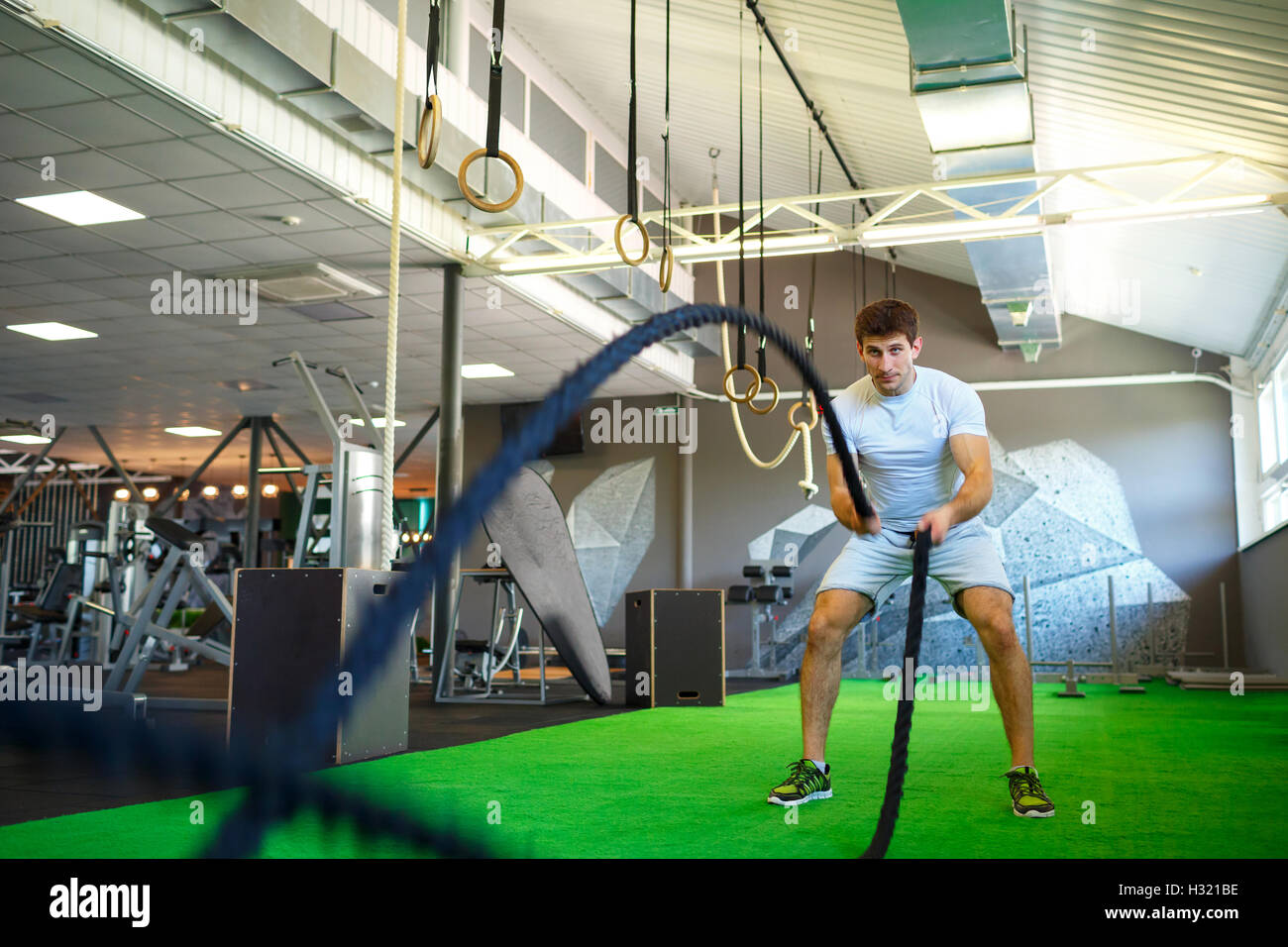 L'homme athlétique bataille avec la corde dans l'entraînement fonctionnel fitness gym Banque D'Images
