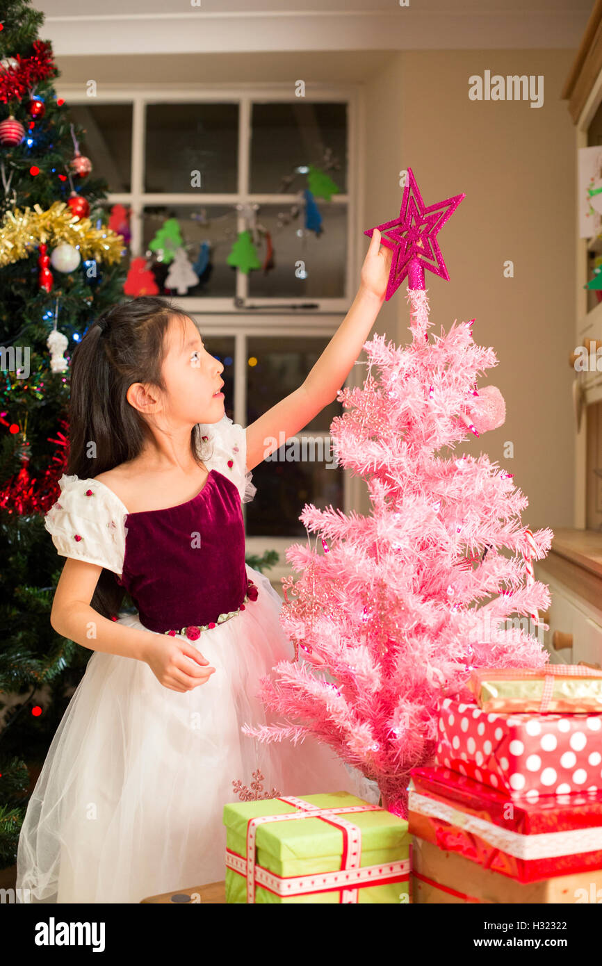 Chinese girl putting une étoile sur son propre arbre de Noël. Banque D'Images