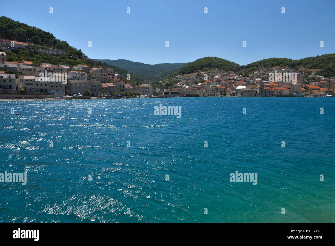 Petit village Pučišća avec eau bleu clair en premier plan, photo de l'île de Brac en Croatie. Banque D'Images