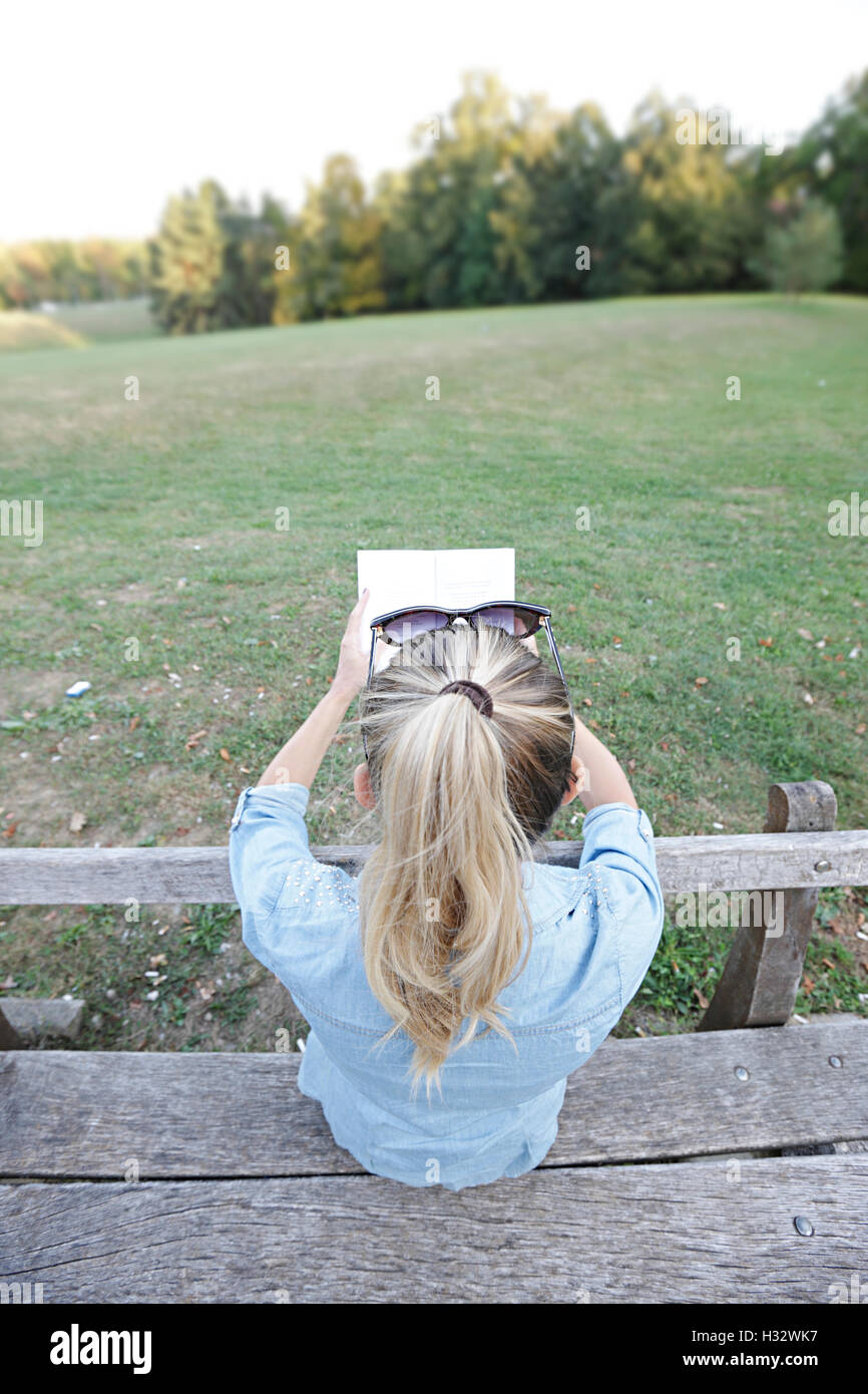 Jeune fille reeding un livre dans le parc Banque D'Images