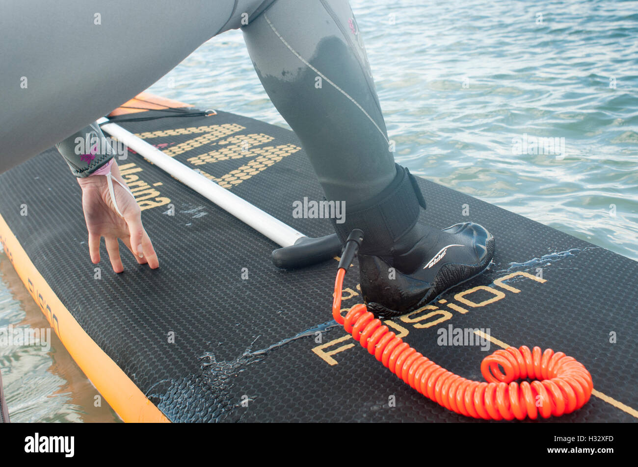 Fille obtenant sur un stand up paddle board, portant une jambe leach Banque D'Images
