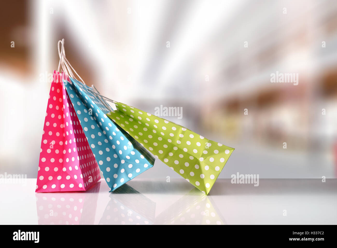 Trois sacs en papier pour l'achat de couleur avec des cercles blancs sur tableau blanc réfléchissant dans un centre commercial. Vue avant Banque D'Images