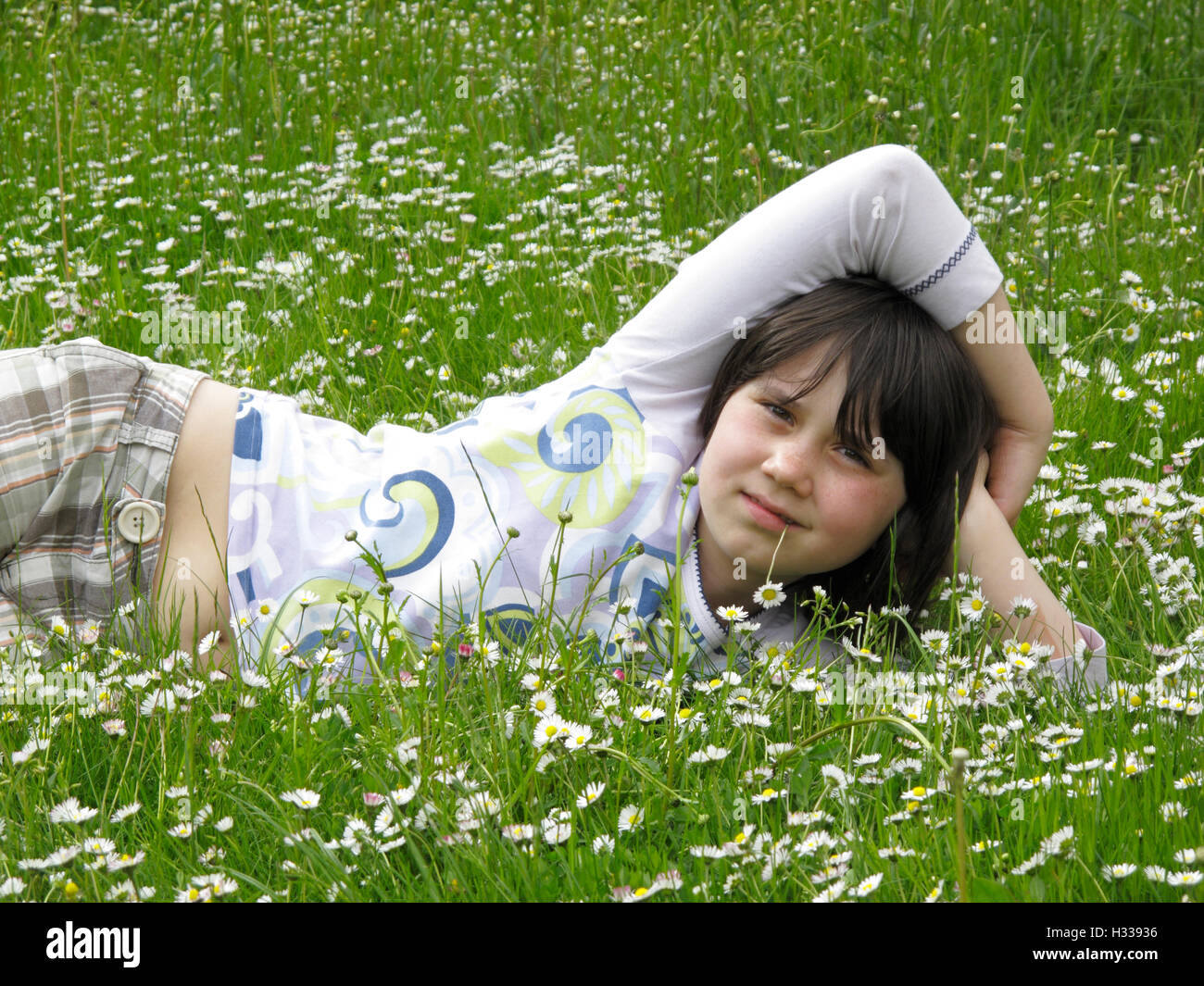 Fille, 8 ans, allongé sur meadow Banque D'Images
