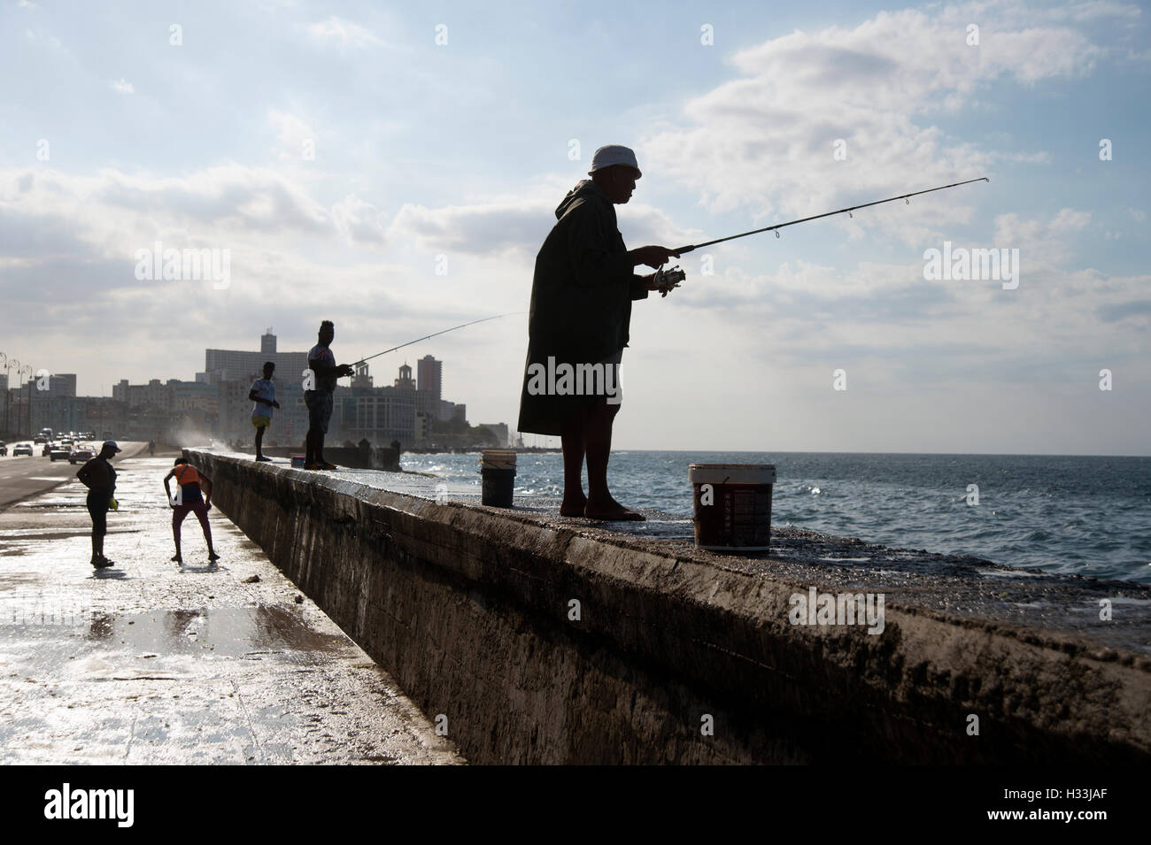 Un groupe de pêcheurs cubains se découpant sur la digue sur le Malecon à La Havane Cuba Banque D'Images