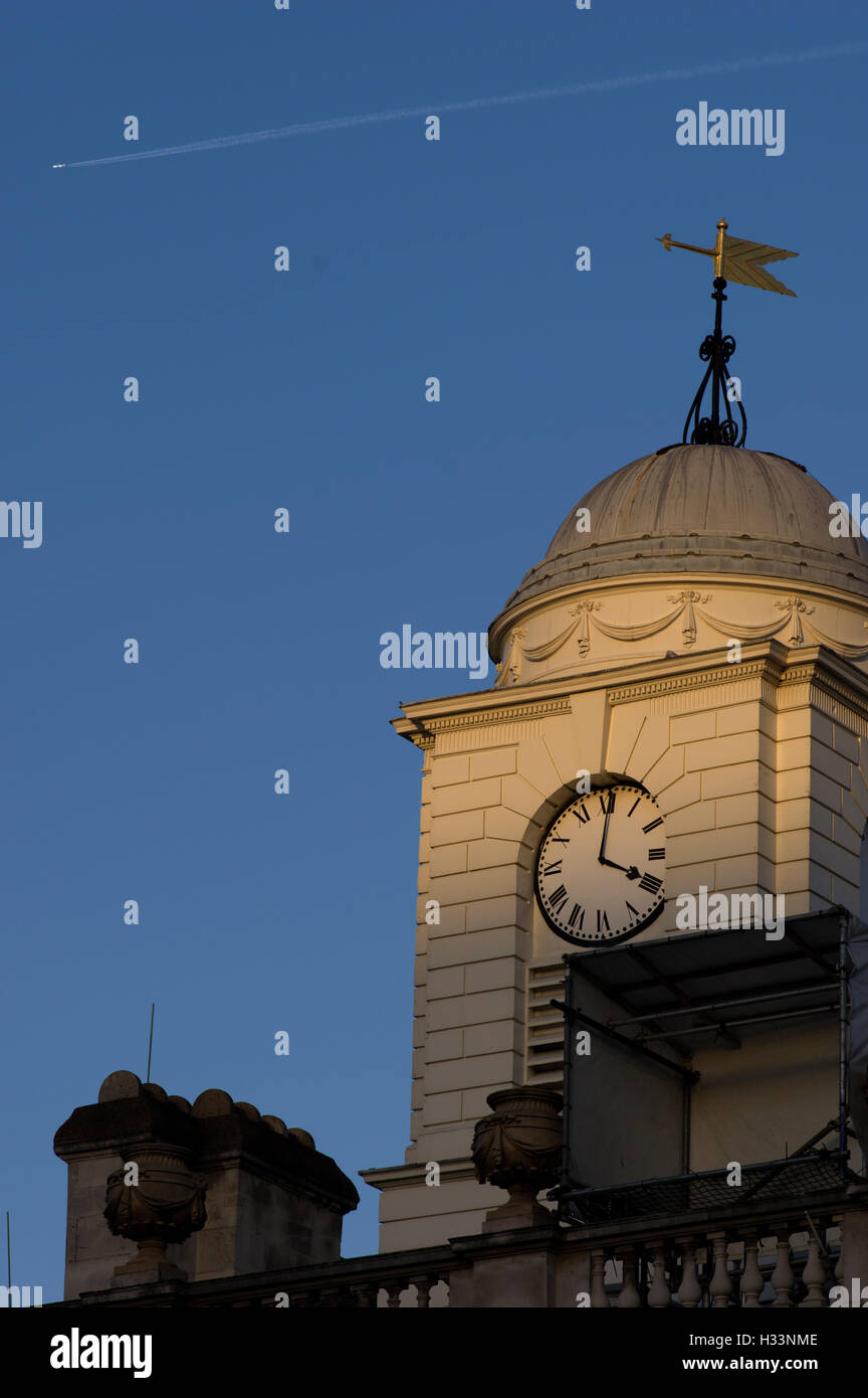 Tour de l'horloge de l'église dans le coucher du soleil avec une girouette contre un ciel bleu profond Banque D'Images