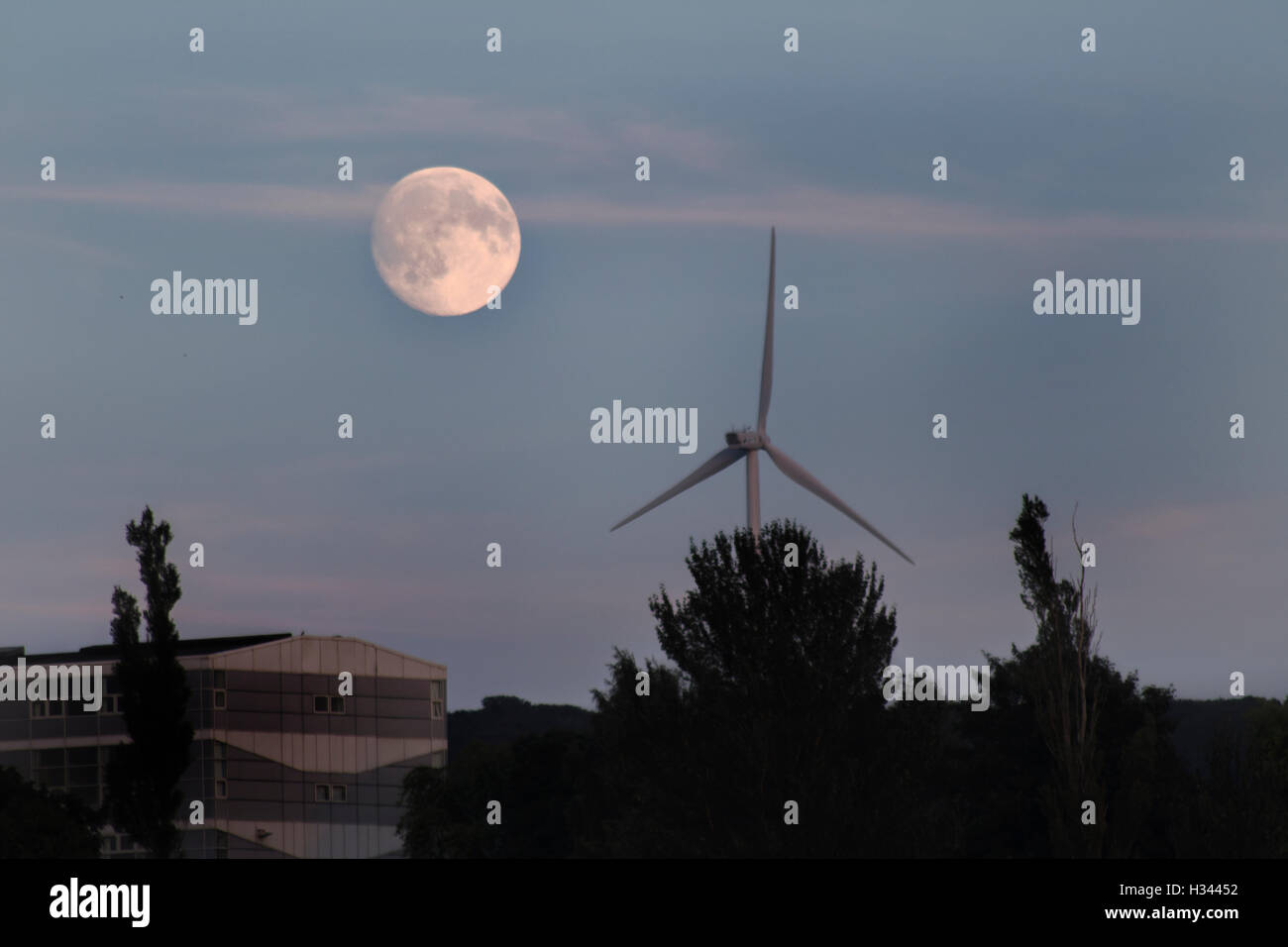 Pleine lune s'élève au-dessus de Glasgow, dans un bâtiment avec un moulin à vent et les arbres, et ciel bleu Banque D'Images