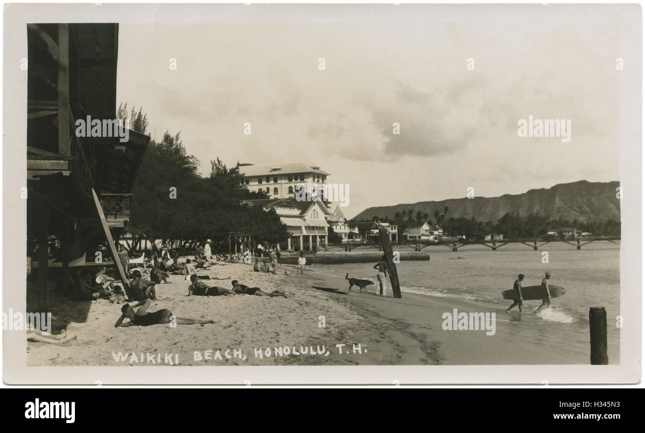 Scène de plage de Waikiki avec baigneurs, surfeurs et des planches en bois à Honolulu, territoire d'Hawaï, c1920s. Banque D'Images