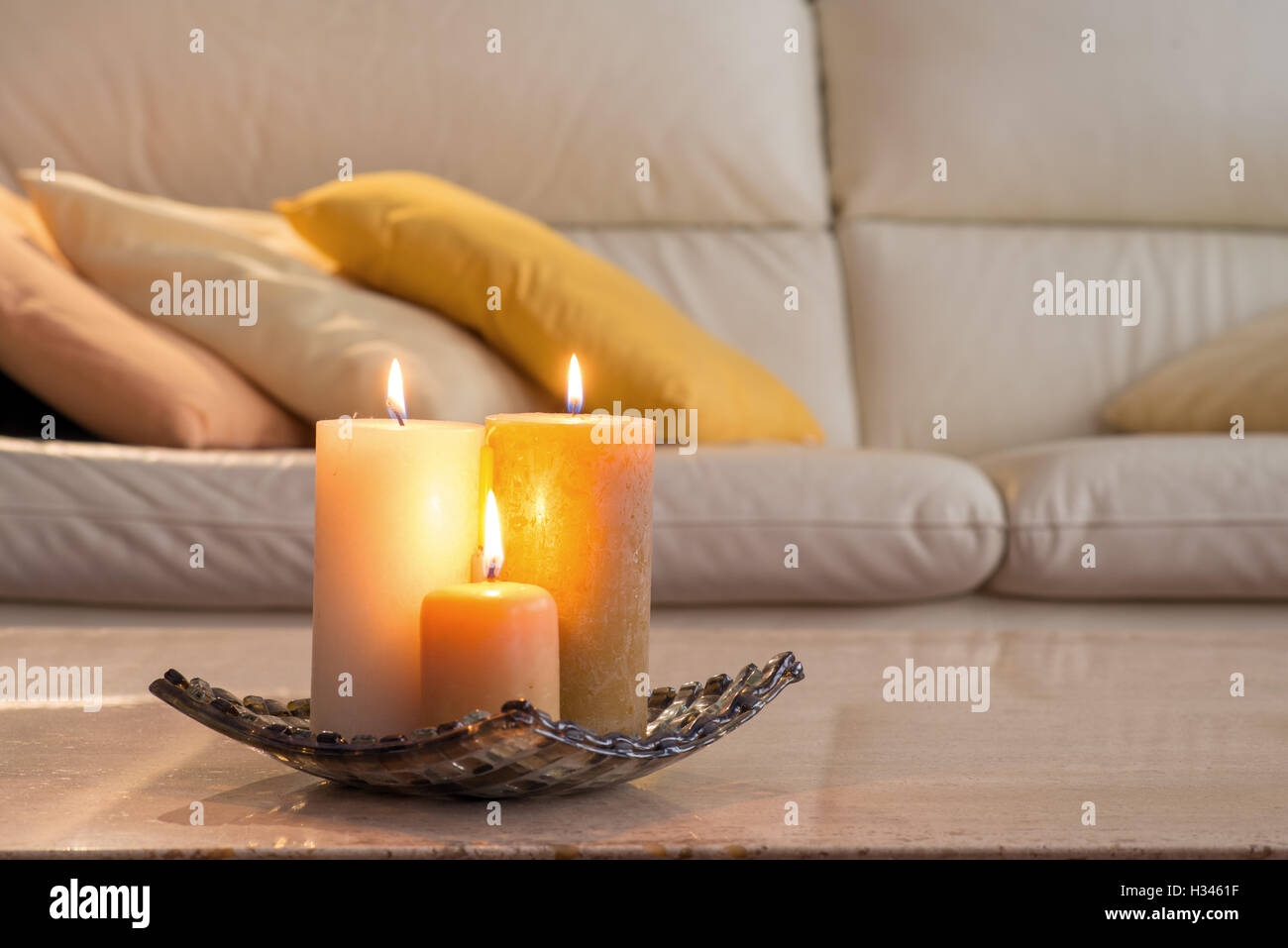Bougies allumées sur une table en marbre et dans le fond d'un canapé avec des oreillers, qui Banque D'Images