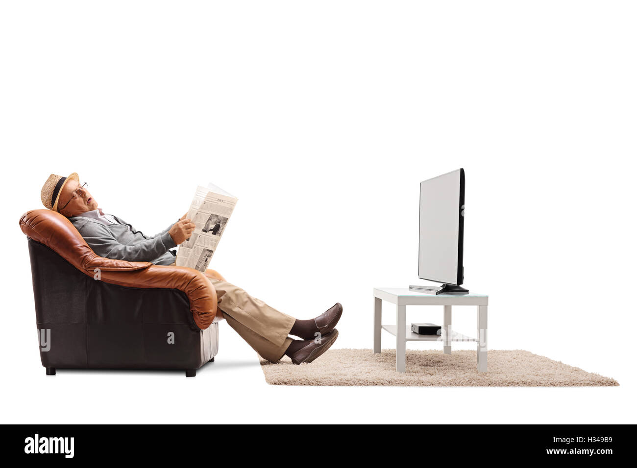 Un homme âgé assis sur un fauteuil tenant un journal et dormir devant la télévision isolé sur fond blanc Banque D'Images