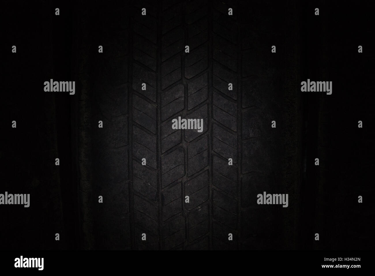 Les pneus de voiture dans une rangée sur une étagère pneu. Close-up dans le noir. Banque D'Images