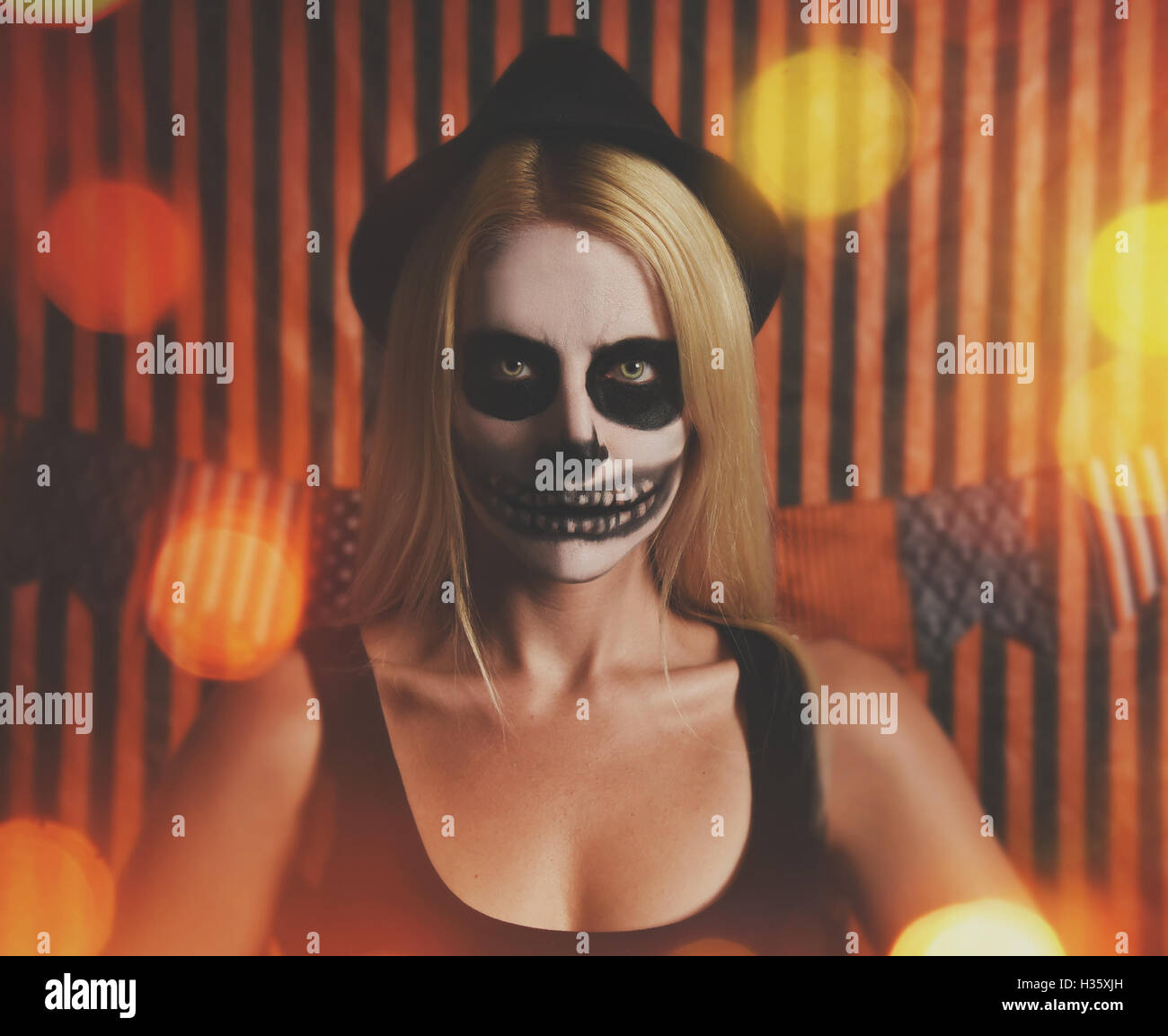 Une femme porte skeleton maquillage sur son visage avec des feux d'un parti d'orange halloween costume ou idée. Banque D'Images