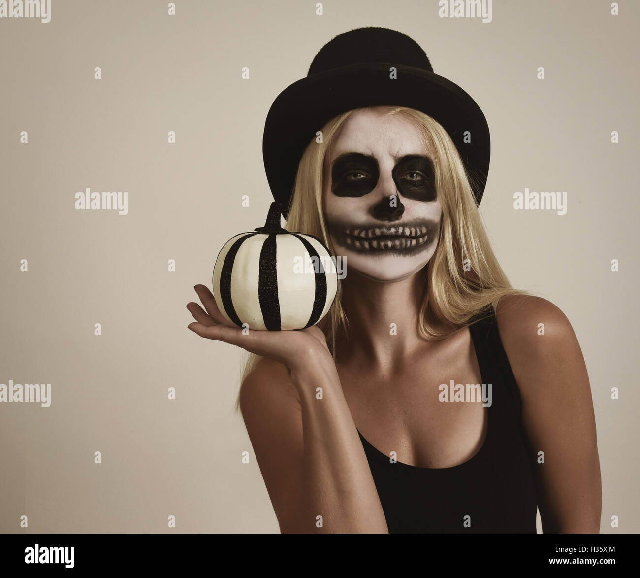 Une fille blonde porte squelette effrayant peinture maquillage sur son visage. Elle est tenue pour une décoration de citrouille halloween message Banque D'Images