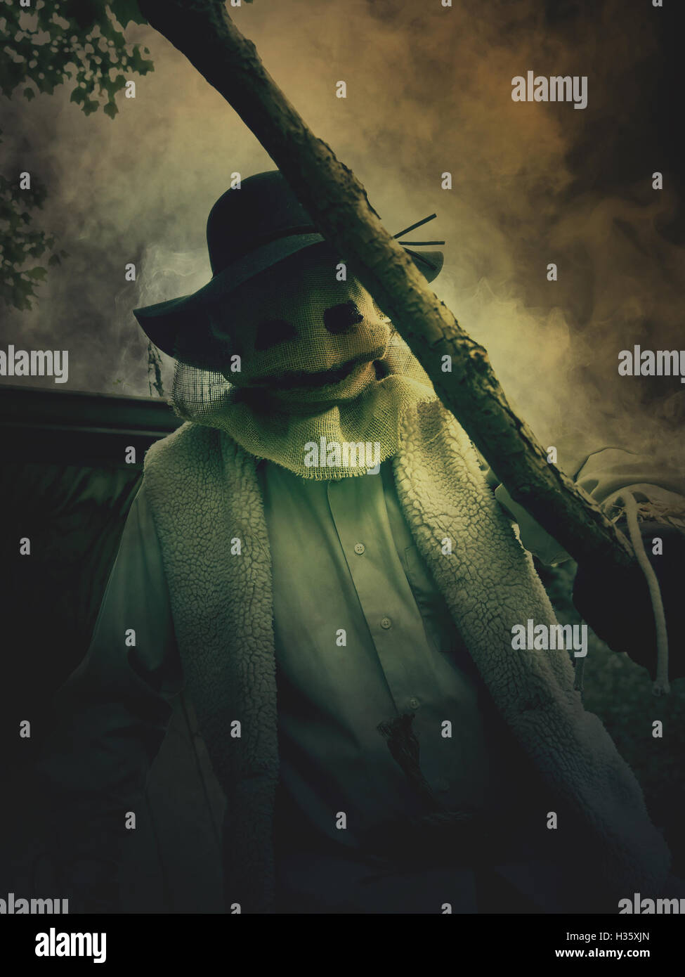 Un peu d'evil scarecrow l'homme est titulaire d'un bâton avec un masque de monstre de jute sur son visage pour un cauchemar halloween concept. Banque D'Images