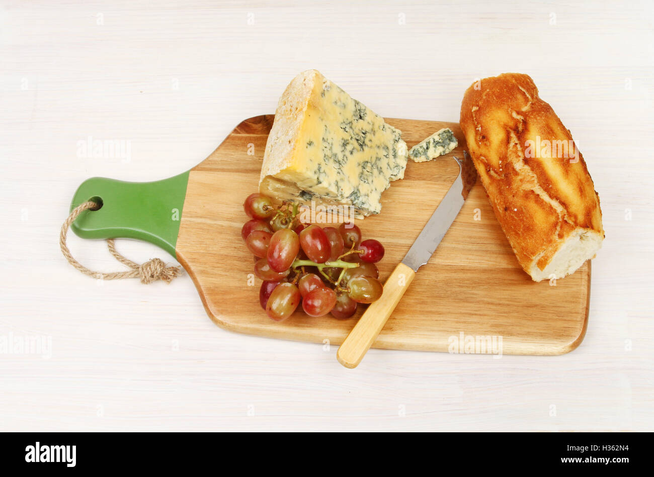 Fromage de stilton, raisins et du pain sur une planche de bois peint blanc Banque D'Images