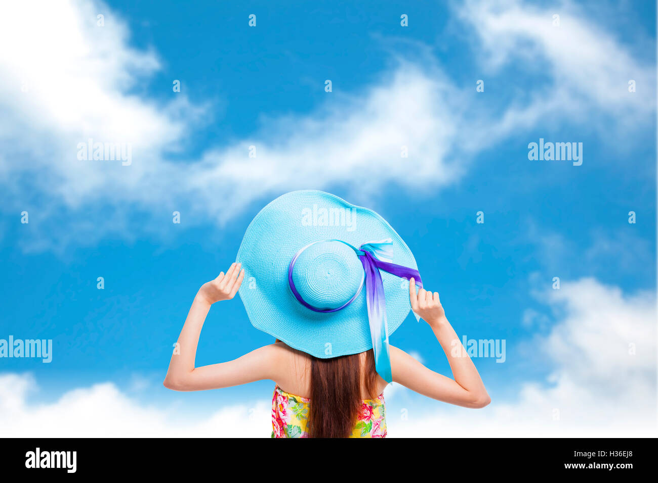 Retour de girl holding a hat avec fond de ciel bleu Banque D'Images