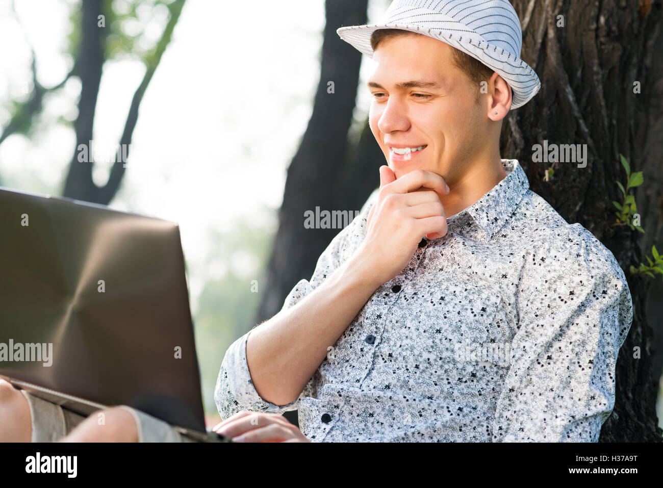 Jeune homme travaillant dans le parc avec un ordinateur portable Banque D'Images