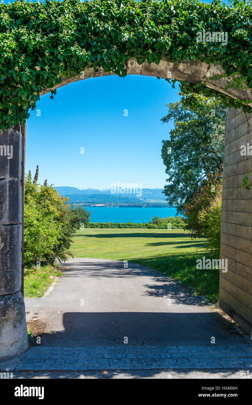 Vue sur le lac de Genève à travers une barrière ouverte dans un mur en pierre recouverte de lierre, Nyon, canton de Vaud, Suisse Banque D'Images