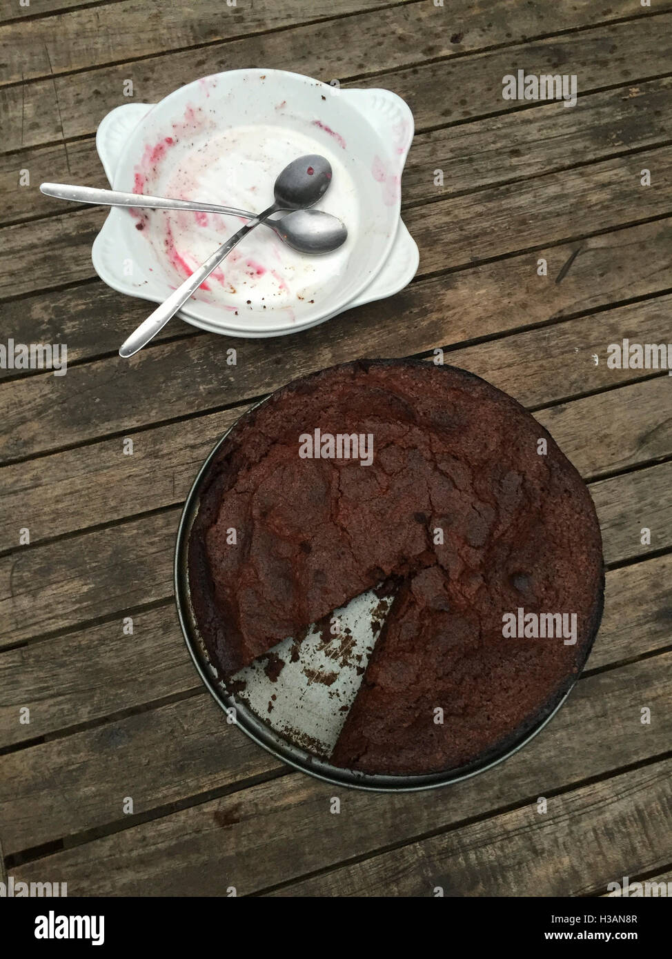 Dans un moule à gâteau au chocolat avec des morceaux manquant et deux plats vides avec cuillères Banque D'Images